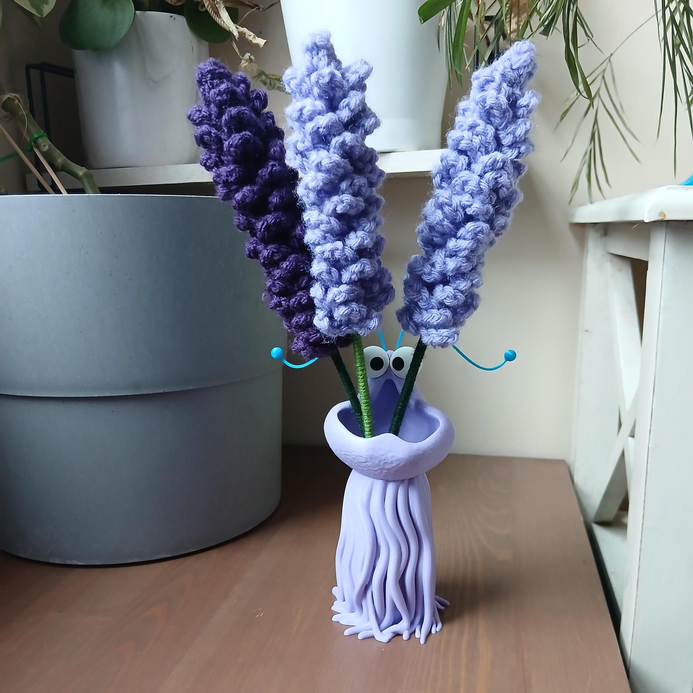 Purple vase with knitted lavender on a wooden surface